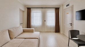A room with a sofa, a chair, a television, and a door with a sign.