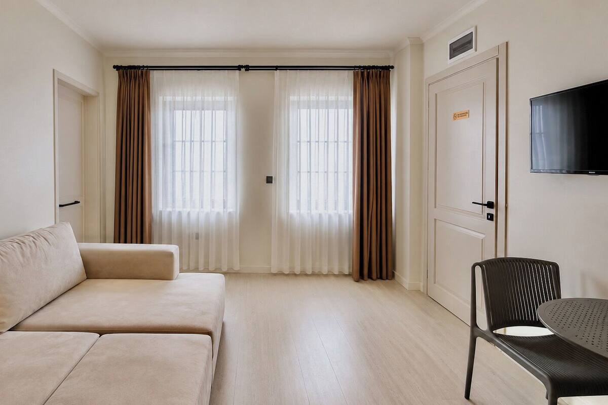 A room with a sofa, a chair, a television, and a door with a sign.