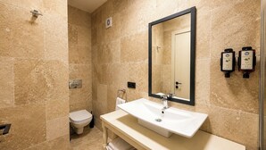 A bathroom with a white sink, a large mirror, and two hand soap dispensers.
