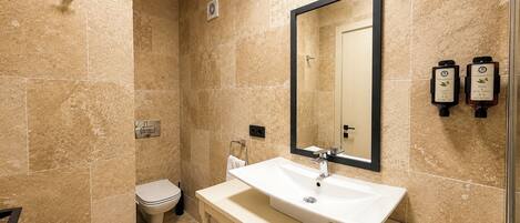 A bathroom with a white sink, a large mirror, and two hand soap dispensers.