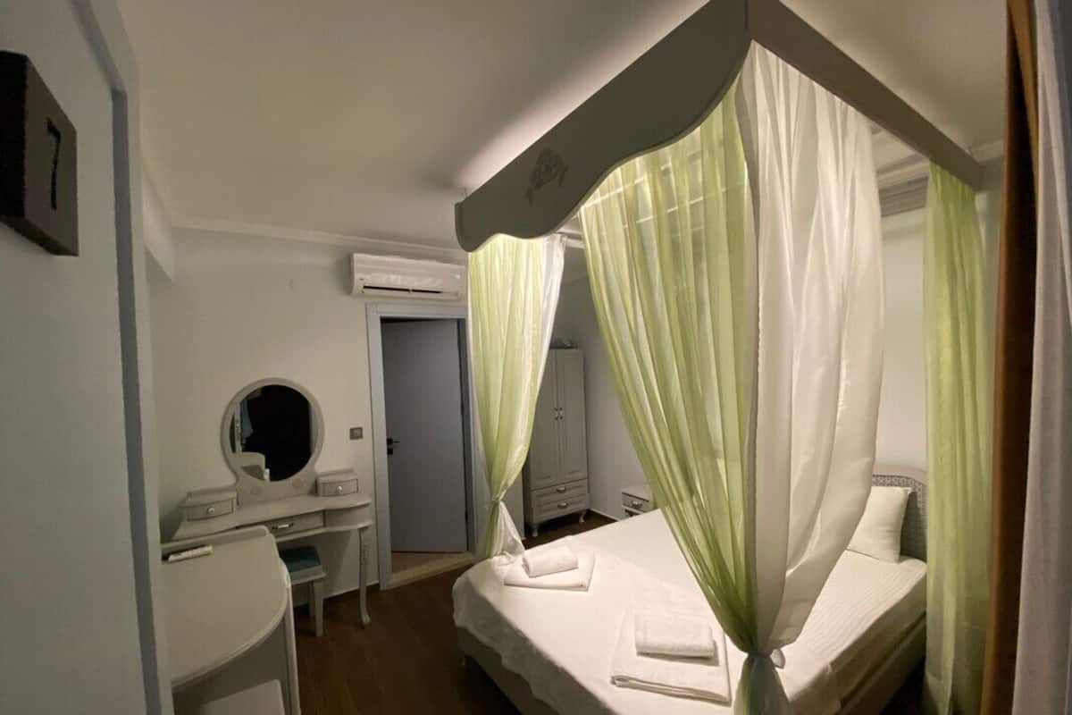 Une chambre à coucher avec un lit à baldaquin, une table de chevet, un miroir et une armoire.