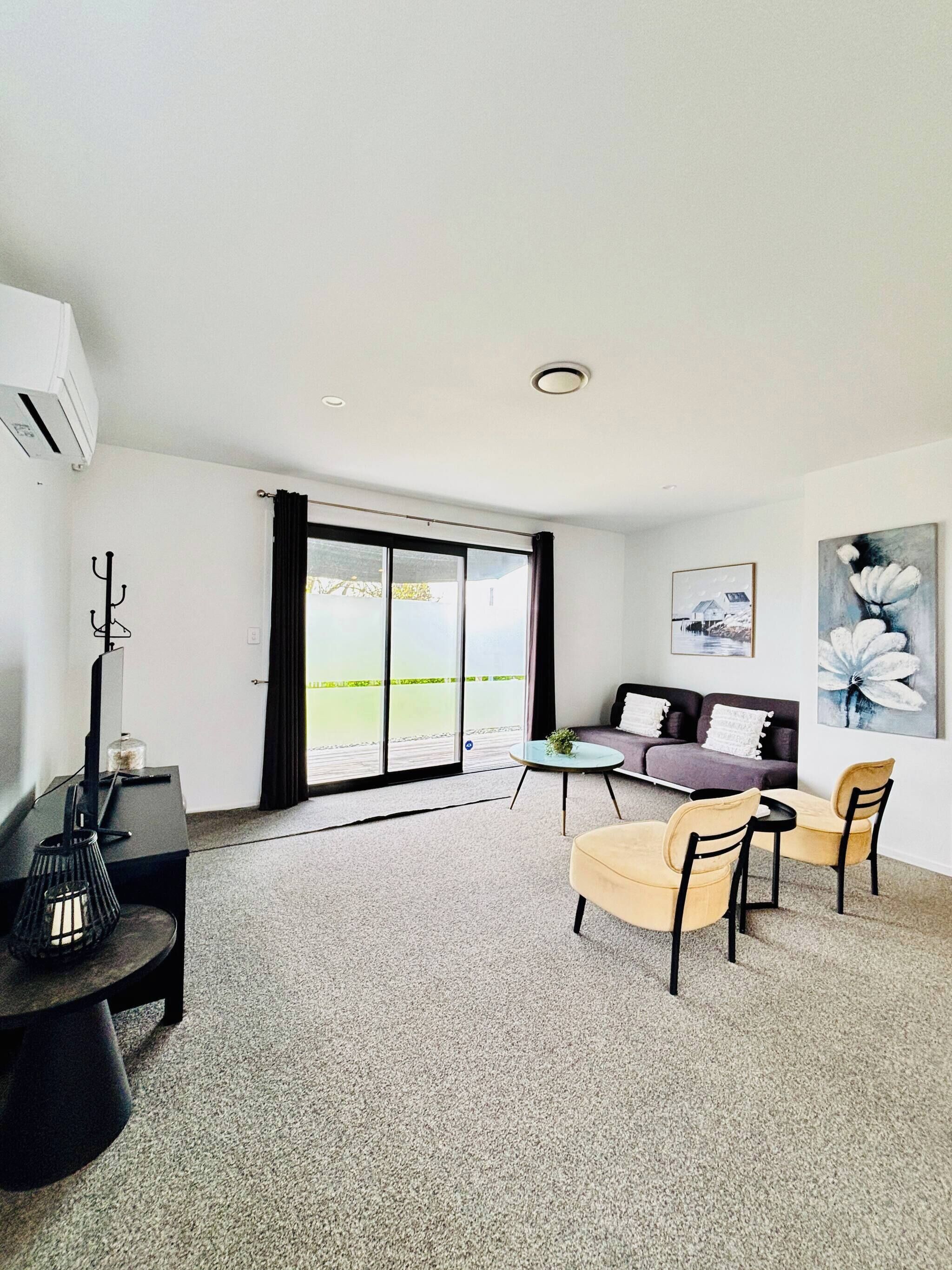 A modern living room with a sofa, chairs, a coffee table, and a large window with curtains.