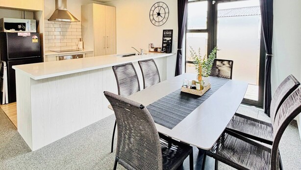 Una cucina moderna con mobili bianchi, un frigorifero nero e un piano cottura integrato.