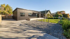 Una casa moderna a due piani con vialetto in cemento, sentiero in ghiaia e prato curato.