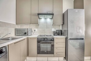 Een moderne keuken met roestvrijstalen apparatuur, een magnetron en een vaatwasser.