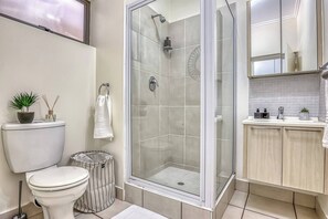 Een badkamer met toilet, bidet, douche en wastafel met spiegel.