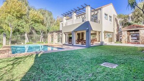 Una moderna casa a due piani con piscina, patio coperto e rivestimento in pietra.