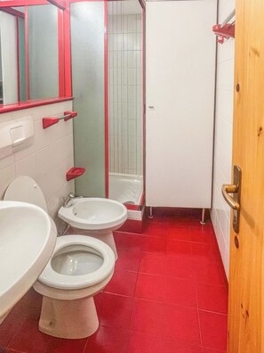 Un baño con dos inodoros, un lavabo, un espejo y una ducha.