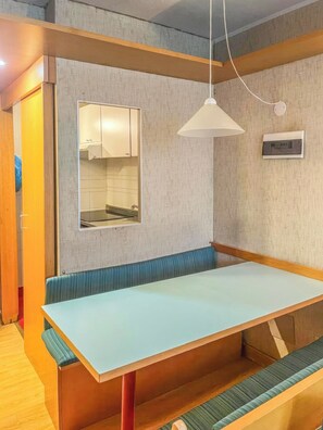 Una habitación con una larga mesa, bancos, un espejo y una lámpara en el techo.