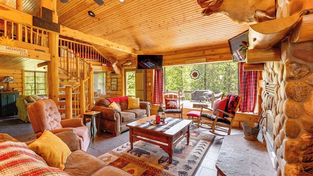 Ein gemütliches Lodge-Interieur mit Holzbalkendecke, Kamin, Fernseher und Essbereich.