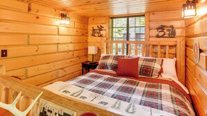 Ein Holzblockhaus-Interieur mit einem Bett, einem Nachttisch, einem Fenster mit Aussicht und einer an der Wand befestigten Uhr.