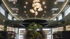 A lobby with a central plant, seating area, and a ceiling with recessed lighting and air vents.
