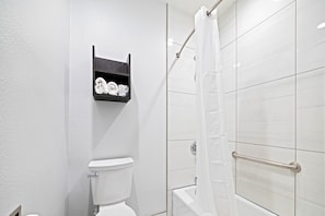 A bathroom with a toilet, a shelf with towels, and a shower area with a glass door.
