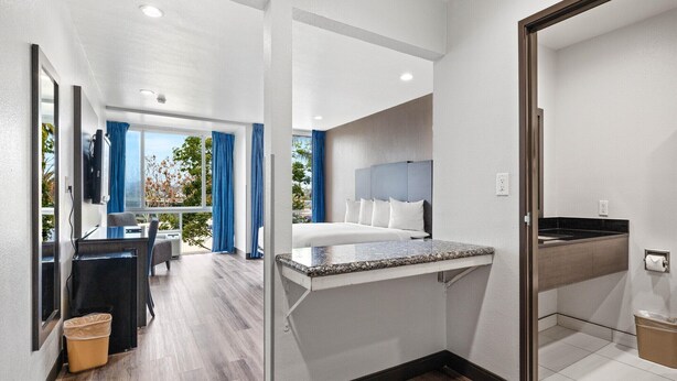 A modern hotel room with a bed, a small desk, a bathroom with a sink, and a view of the outdoors. - 1 Queen Bed|Nsmk,Micfridge,View (Oceanside)