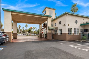 A gas station with a canopy, palm trees, and a clear sky.