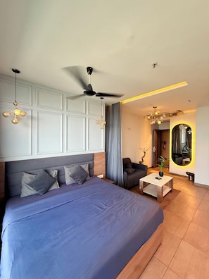 Ein modernes Schlafzimmer mit einem großen Bett, einem Deckenventilator und einer Sitzecke mit Couchtisch.