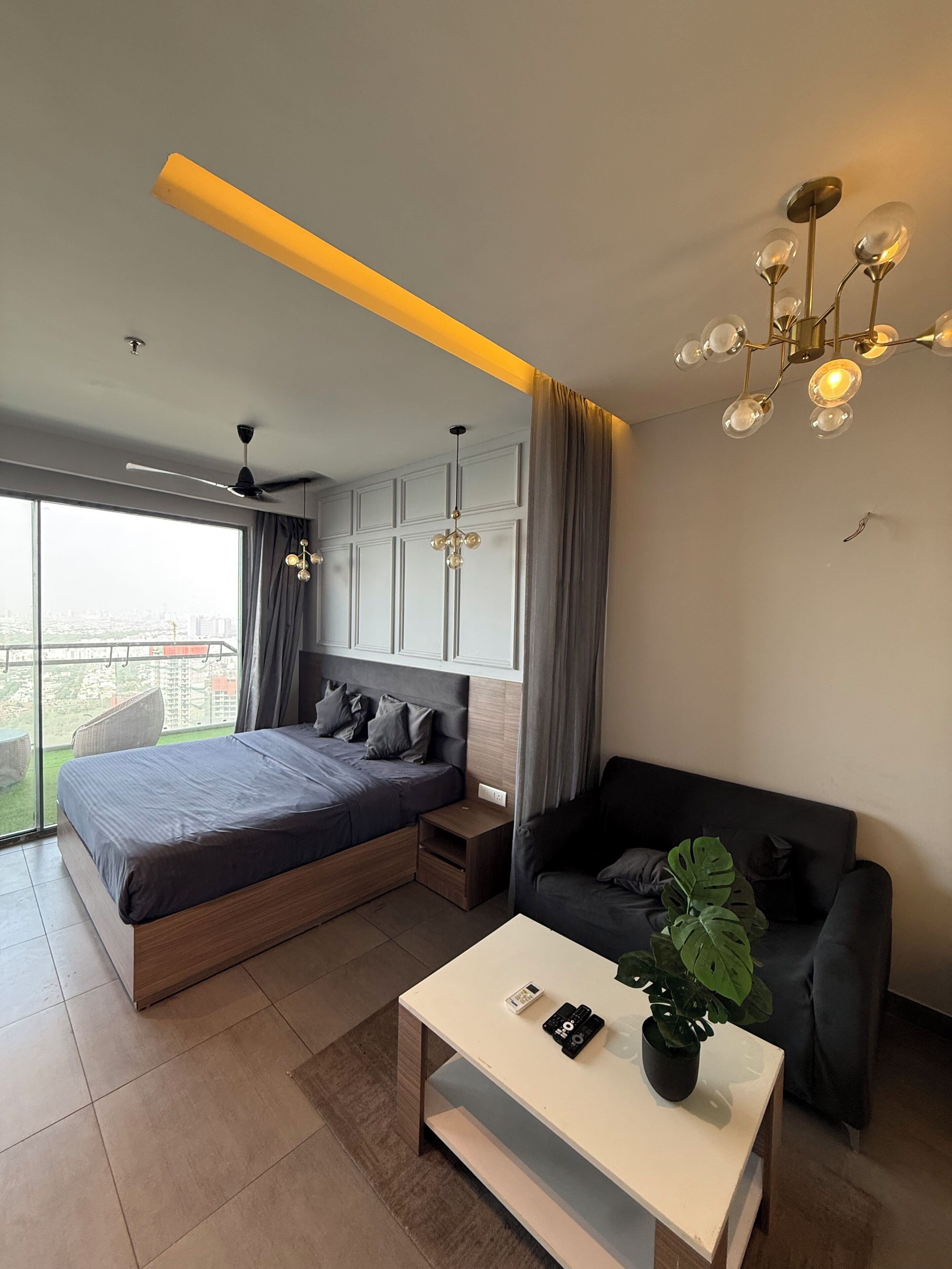 Un dormitorio moderno con cama, sofá, una mesita de centro y un ventanal grande.