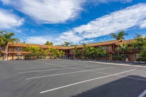 Un hotel con estacionamiento, varias edificaciones y palmeras.