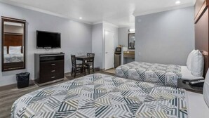 A hotel room with two beds, a TV, a desk, and a mirror.