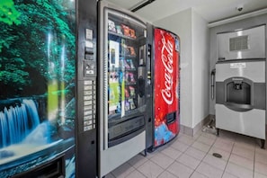 Automaatti, jossa on Coca-Colan logo, vesihana ja digitaalinen näyttö, jolla esitetään vesiputous.