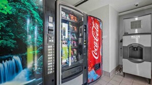 A vending machine with a Coca-Cola logo, a water dispenser, and a glass display case with various items.