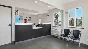 A reception area with a counter, two chairs, a window with a view, and a wall-mounted air conditioning unit.