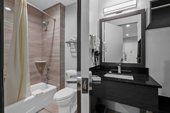 Une salle de bain moderne avec une baignoire, des toilettes et un grand miroir au-dessus du lavabo.