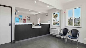 A reception area with a counter, two chairs, a window with a view, and a wall-mounted air conditioning unit.