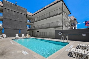 Una piscina amb gandules i un edifici amb balcons.