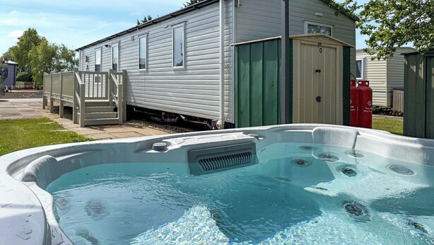 Een jacuzzi voor een stacaravan met een overdekte veranda en een brandblusser.