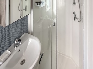 A bathroom with a white sink, a mirror, and a glass shower enclosure. - Horse Shoe Lakes - UKC9581 (Mablethorpe)