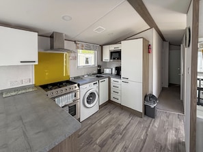 A compact kitchen with a stove, washing machine, microwave, and cabinets. - Horse Shoe Lakes - UKC9581 (Mablethorpe)
