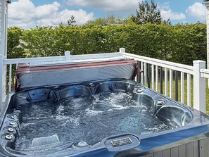 Ein Whirlpool mit Metallgestell, Bedienfeld und Geländer aus Holz.