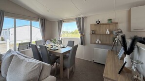 Une chambre meublée comprenant une table à manger, des chaises, un canapé, un radiateur et une fenêtre avec des rideaux.
