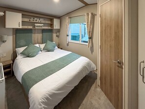 Ein Schlafzimmer mit einem Bett, einem Fenster mit Vorhängen, einem Kleiderschrank und einem Regal mit einem 'LOVE'-Schild.