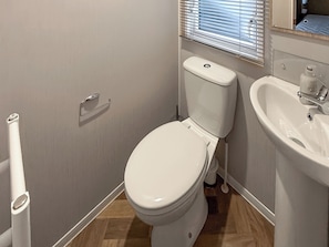A bathroom with a toilet, sink, and window blinds. - Golf Village 107 - UKC9578 (Mablethorpe)