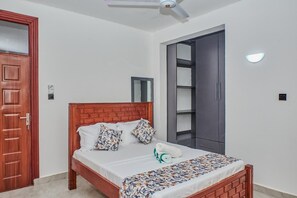 Une chambre à coucher avec un lit en bois, une porte, une armoire et un ventilateur de plafond.