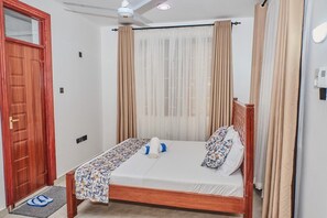 Ein Schlafzimmer mit einem hölzernen Bett, einer Tür und einem Deckenventilator.