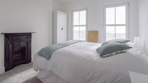 Une chambre à coucher avec un lit, une cheminée et deux fenêtres donnant sur un beau paysage.