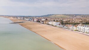 Une ville côtière dotée d’une plage de sable, d’une promenade et d’une rangée de bâtiments le long du littoral.