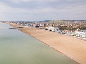 Eine Küstenstadt mit sandigem Strand, einer Promenade und einer Reihe von Gebäuden entlang der Küste.