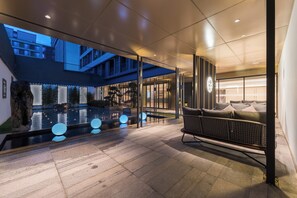A modern hotel lobby with a pool, seating area, and glass walls offering views of the building's interior. - Guangzhou Baiyun Airport Manxin Hotel (guangzhoushihuaduqu)