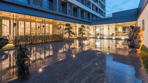 Un hotel moderno con un patio reflectante, amplias ventanas y una entrada bien iluminada.