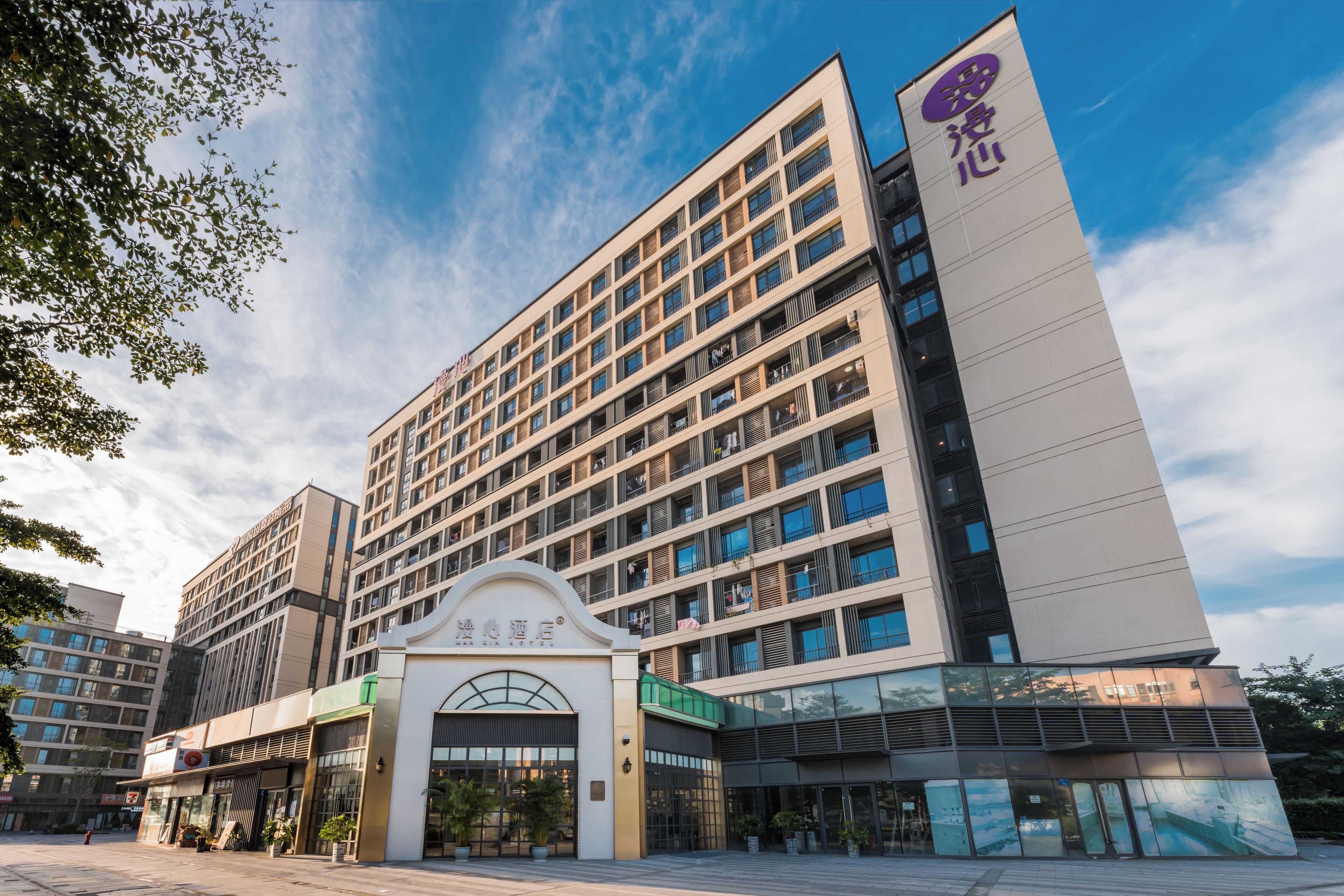 A modern hotel with a prominent entrance, multiple floors, and a clear sky.
