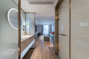 A modern hotel room with a large mirror, a vanity with a sink, a seating area with a sofa and a coffee table, and a view of the city through large windows. - Guangzhou Baiyun Airport Manxin Hotel (Guangzhou)