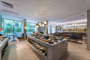 A modern hotel lobby with a central bar area, seating arrangements, and large windows offering a view of greenery. - Guangzhou Baiyun Airport Manxin Hotel (Guangzhou)