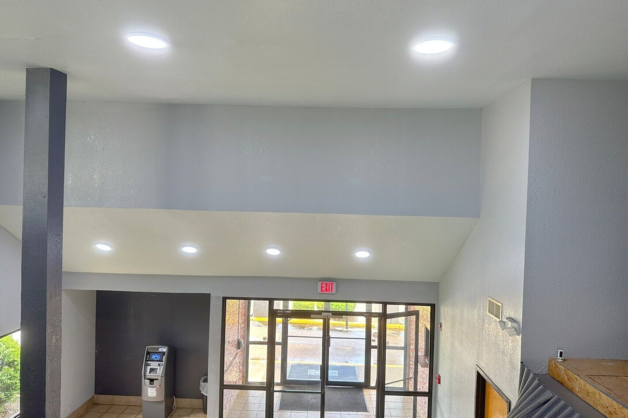 A hotel entrance with an ATM, a glass door, and an exit sign.
