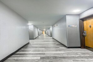 A long, narrow hallway with a wooden floor, white walls, and doors on both sides.