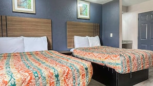 Deux lits simples avec des têtes de lit assorties, une table de chevet en bois et une porte sur le côté droit.