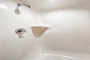 Eine weiße Badewanne mit einem Wasserhahn und einer an der Wand befestigten Duschbrause.